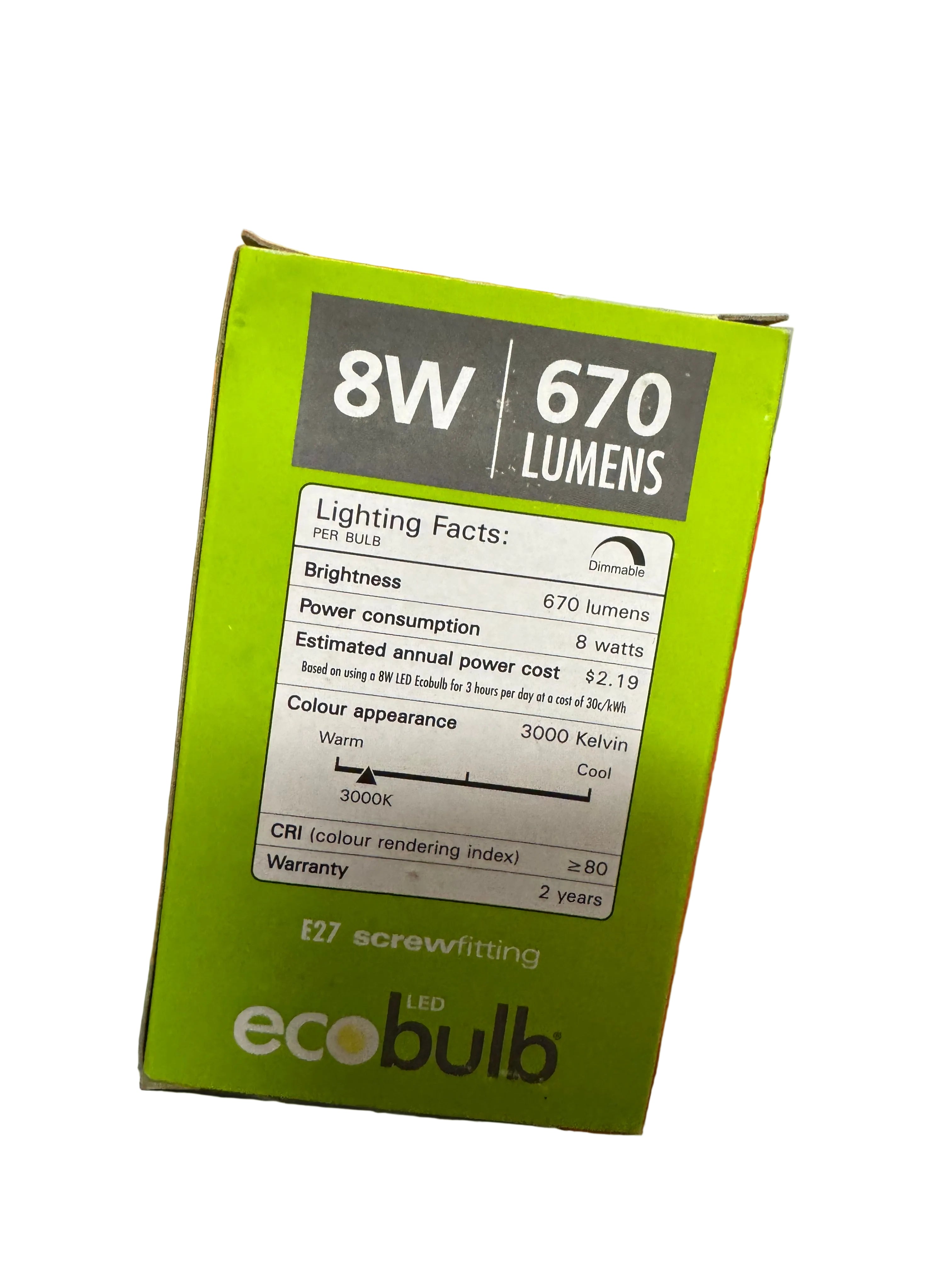 Hand holding a green LED bulb packaging with technical specifications on a red surface.
